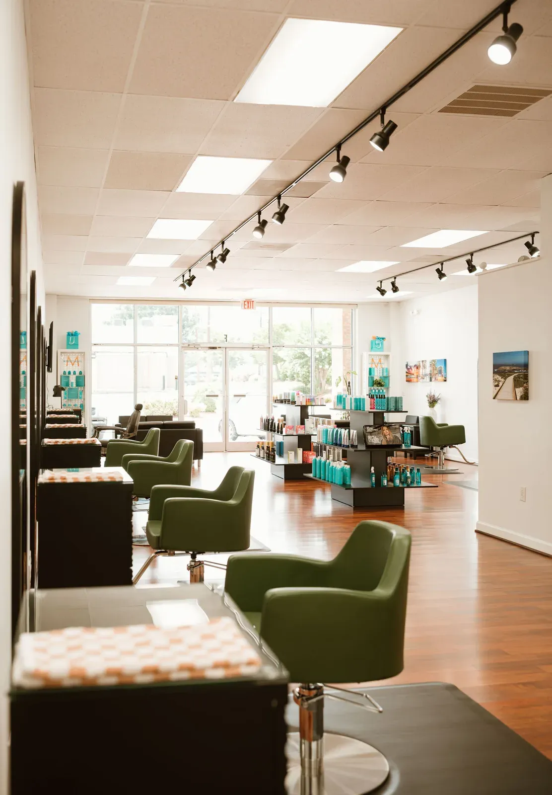 The salon lounge with black sofas, green chairs and a chestnut floor