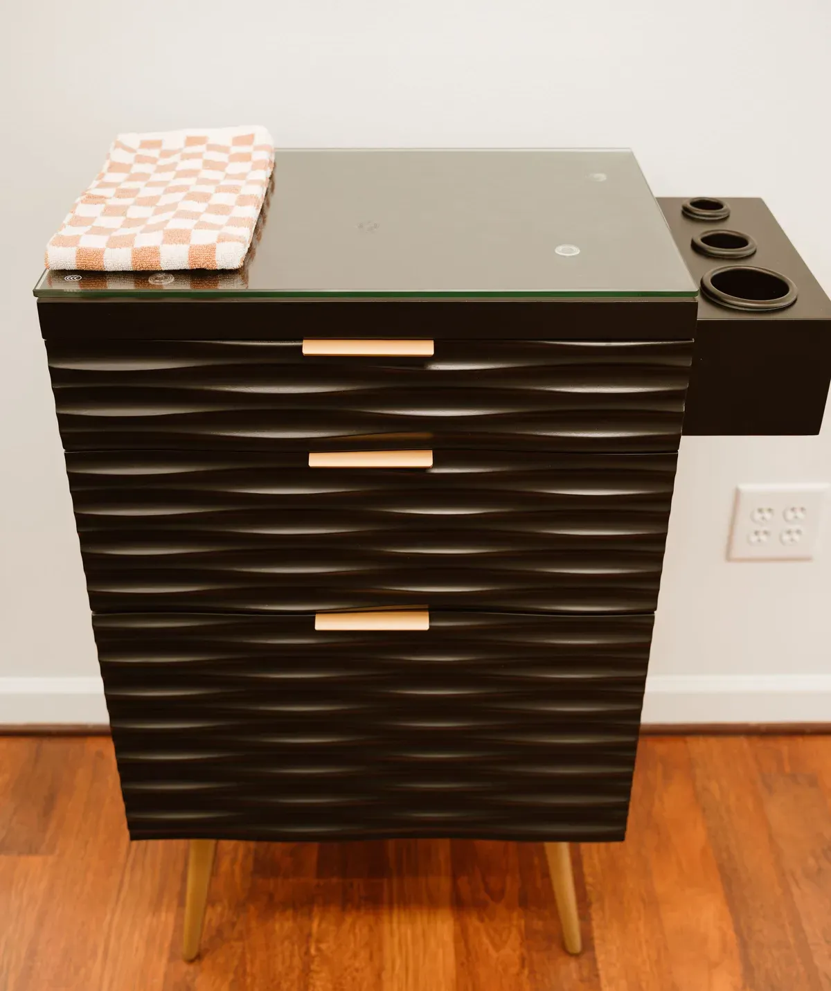 A black ribbed station cabinet with brass pulls