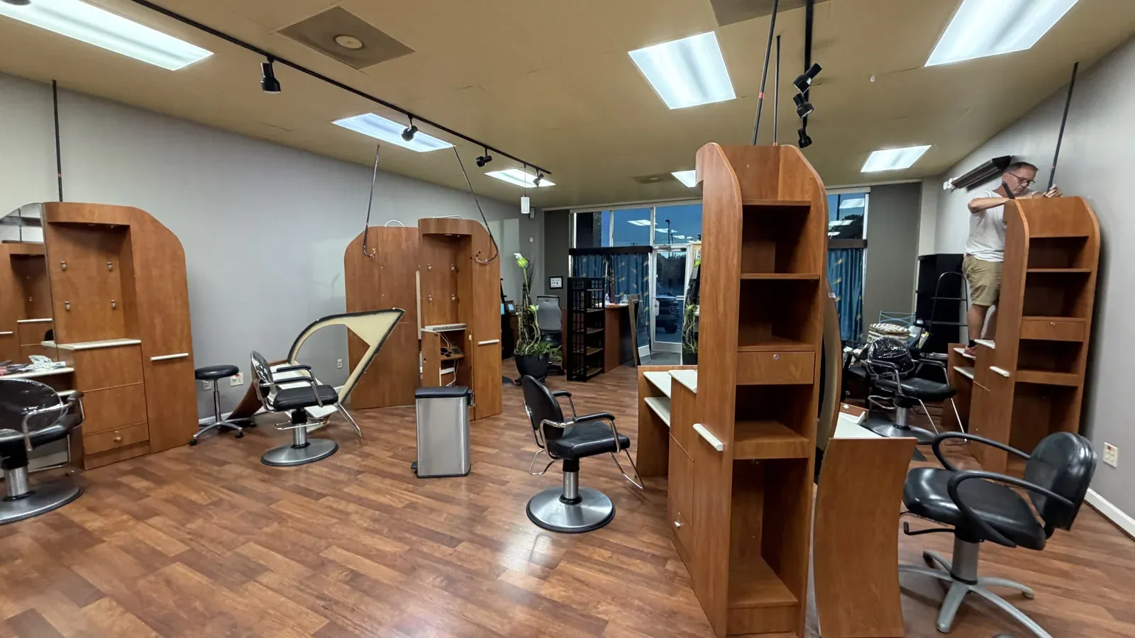 The inherited salon: wooden stations and grey walls before the rebuild