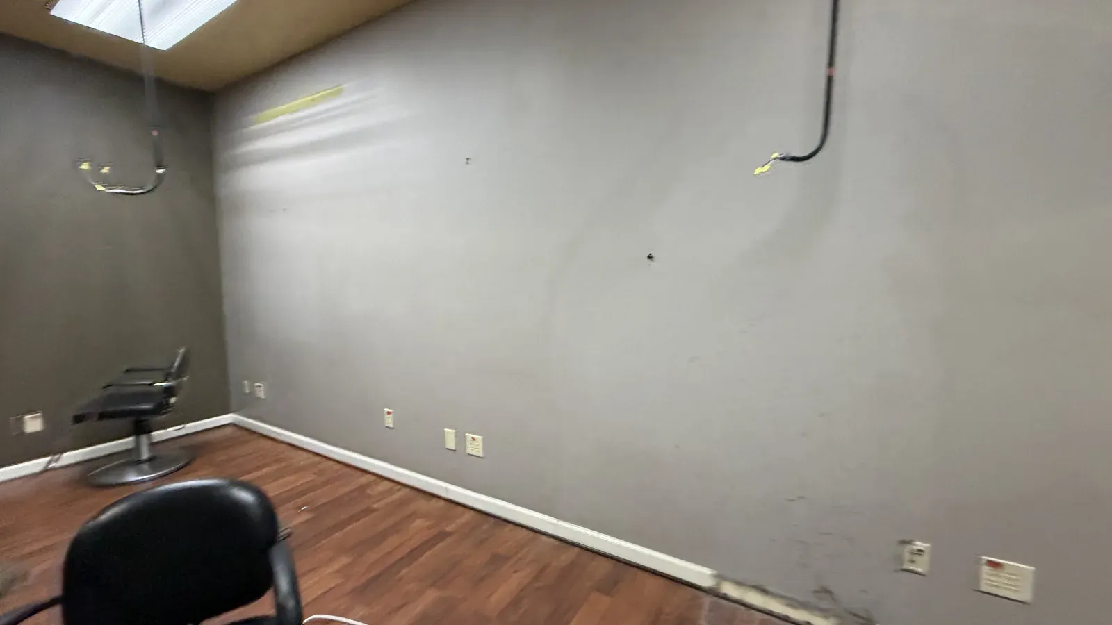 A bare grey wall with old chairs, mid-teardown